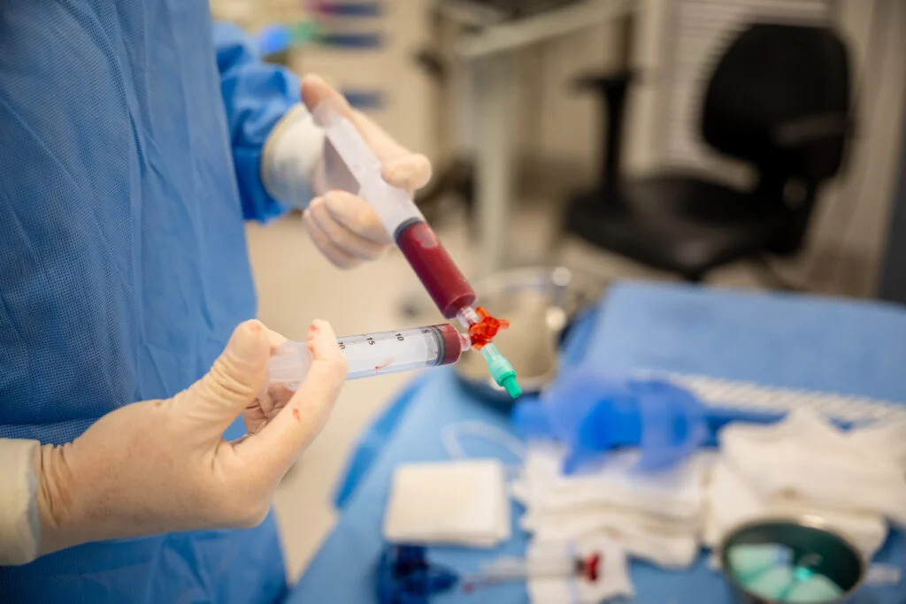 Profissional com luvas manipulando seringas com material biológico